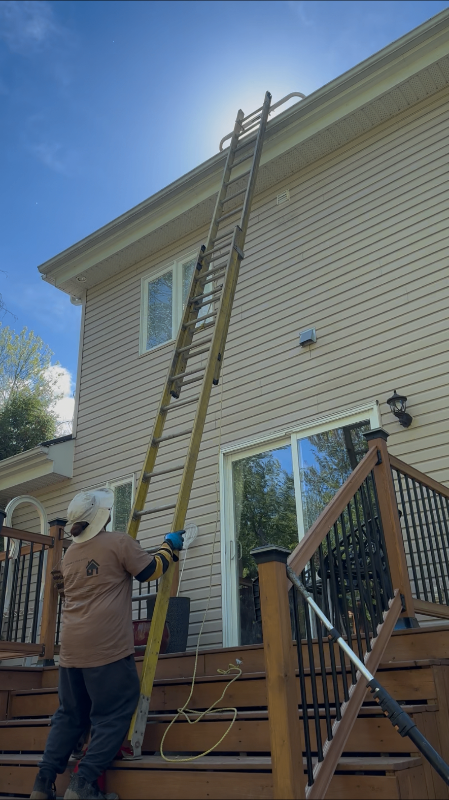Happy Gutters technician cleaning gutters on a two-story home